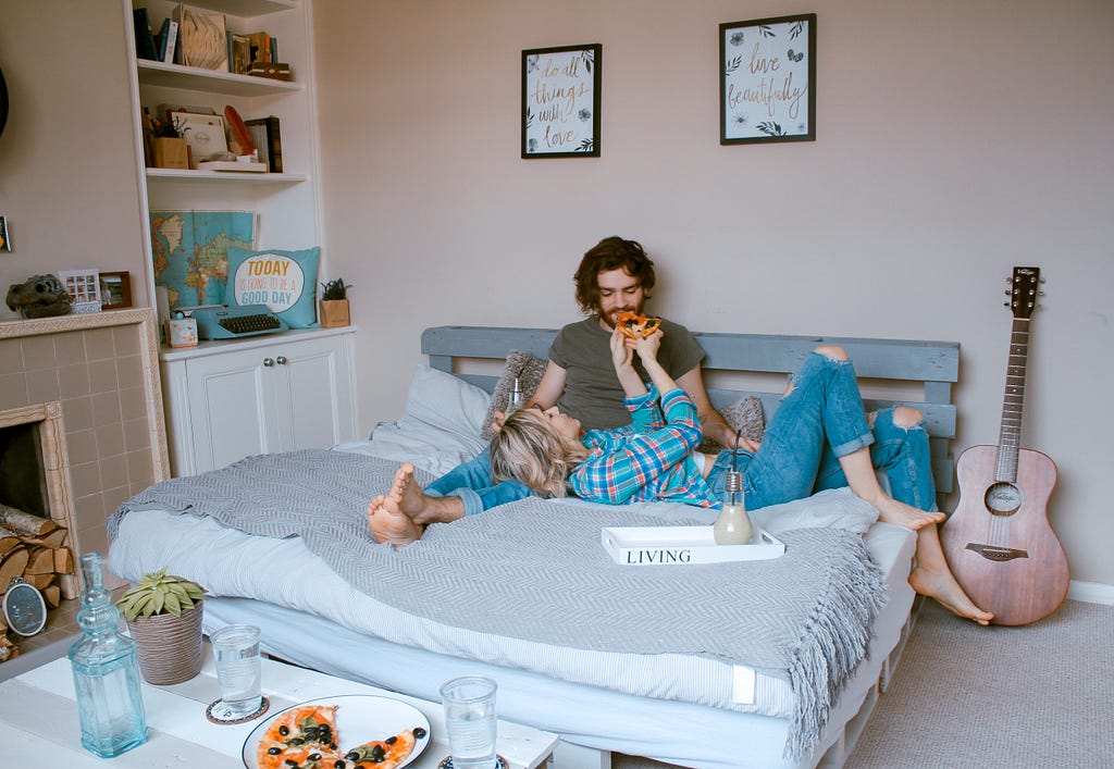 Man and woman lying on the bed and eating.