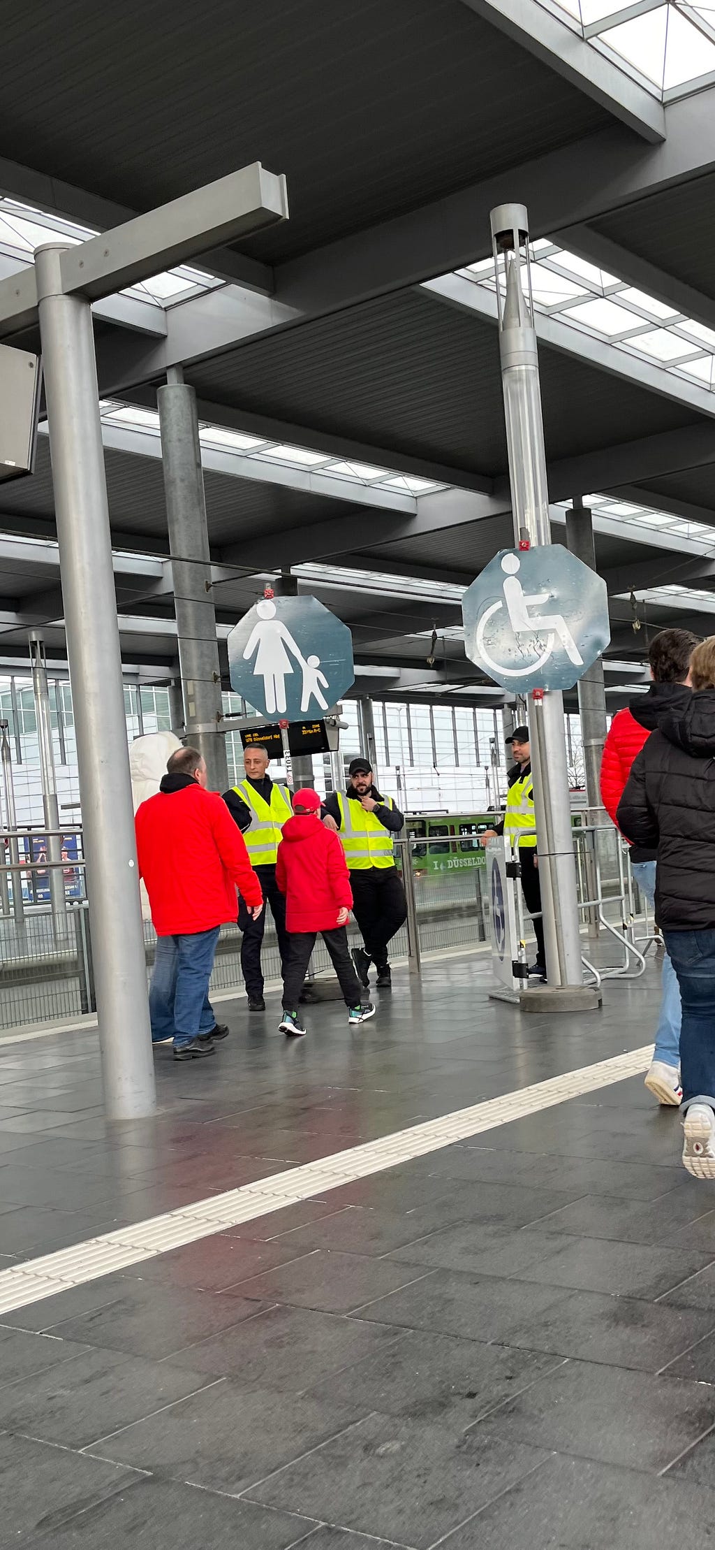 Ein mit drei Ordnern und zwei Schildern gekennzeichneter Eingang für Rollstuhlfahrer und Eltern mit Kind, um sicher und barrierefrei in die U-Bahn zu kommen
