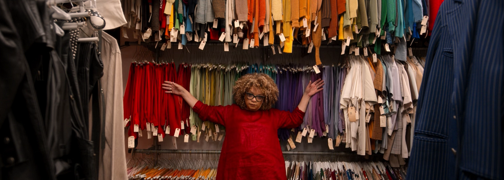 Ruth Carter leaning against a backdrop of colorful costumes on racks