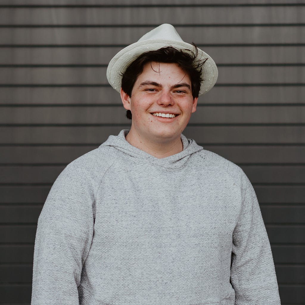 A handsome individual posing with his professors infamous fedora.