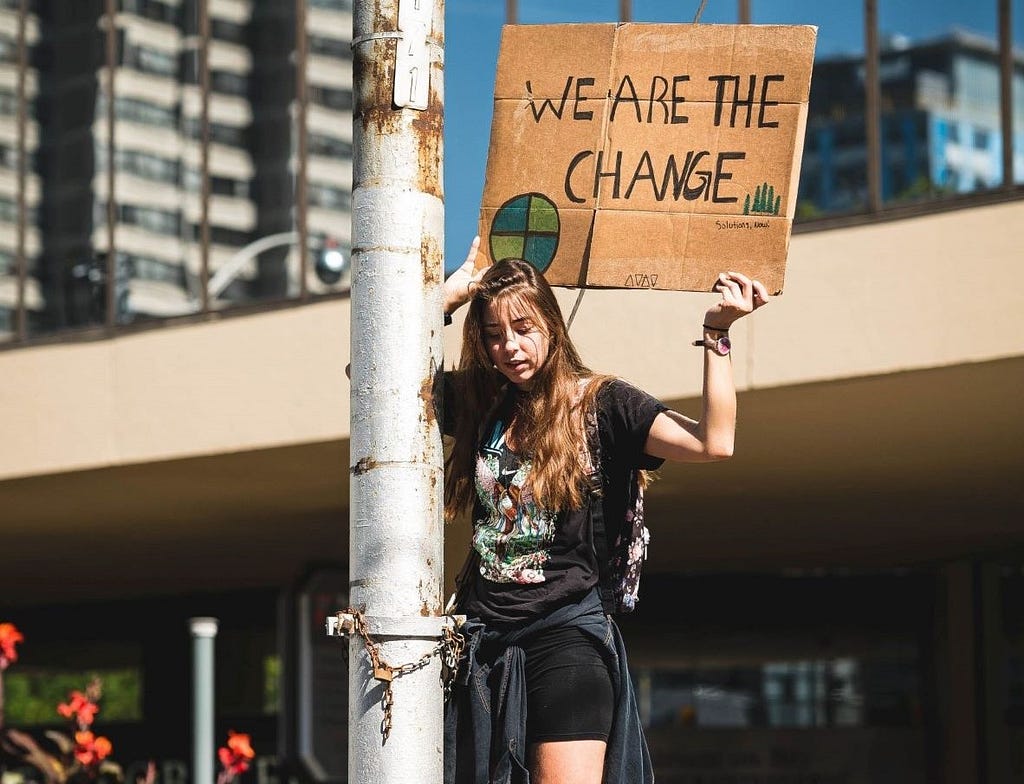 Woman holding a “We are the change” sign at Climate protest