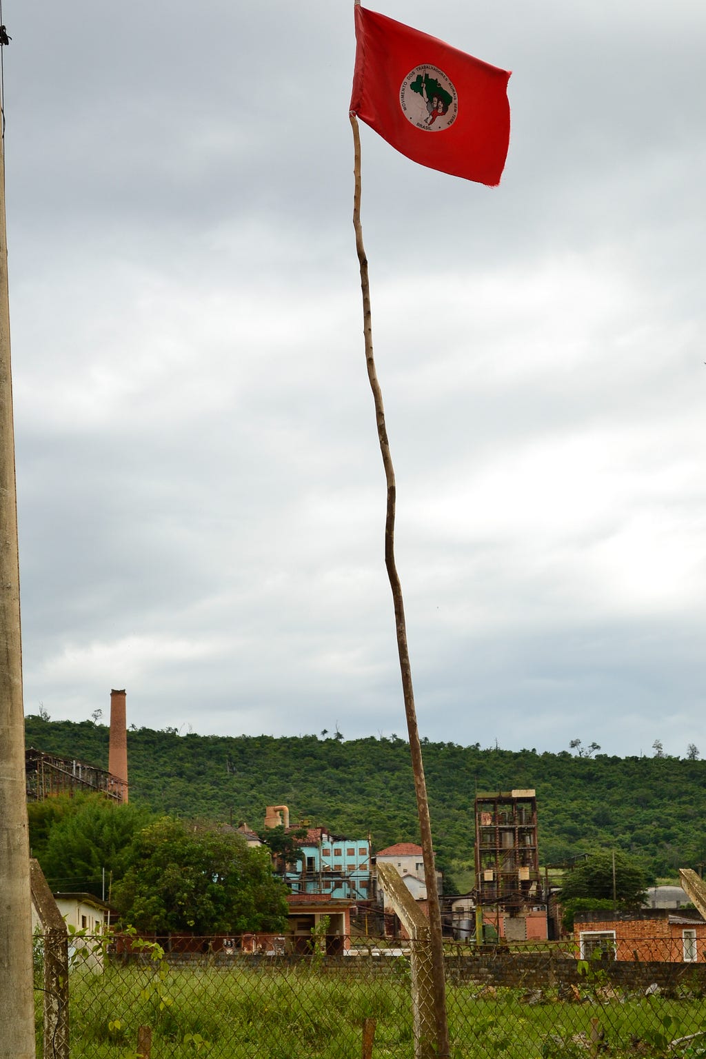 Bandeira do MST, na escola do assentamento, em primeiro plano. Ruínas da Usina de Ariadnópolis ao fundo.