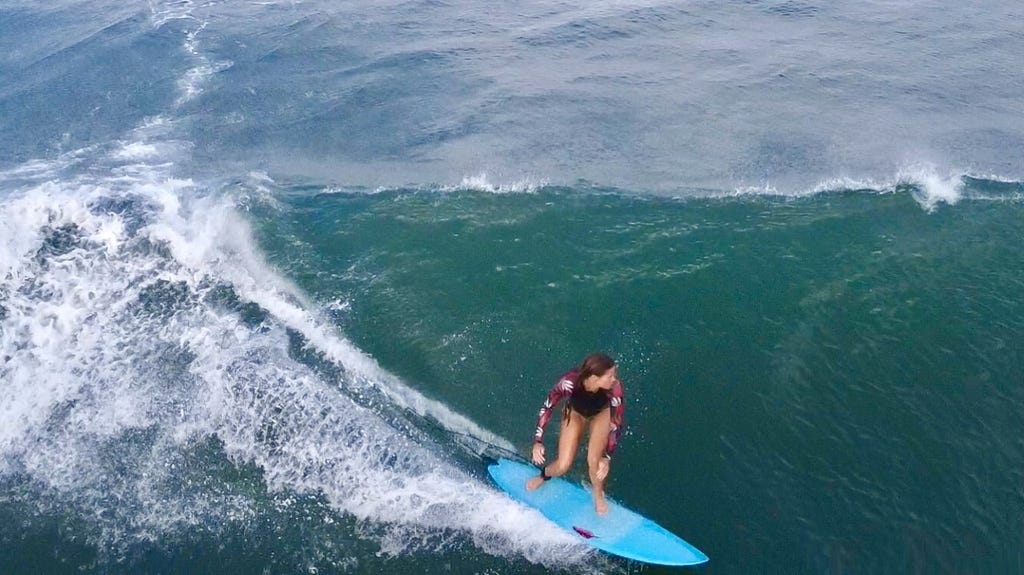 Surfing a head-high wave with a blue shortboard.