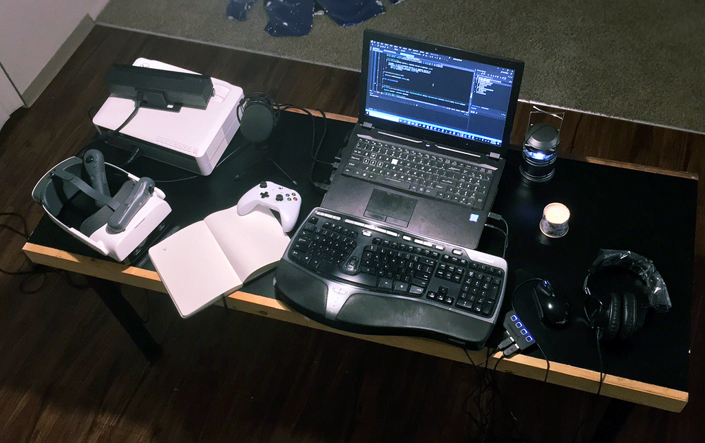 Laptop, keyboard, VR headset and game controllers.