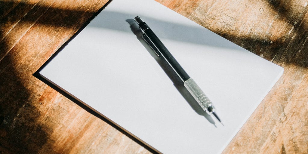 A plank piece of paper with a mechanical pencil resting on top