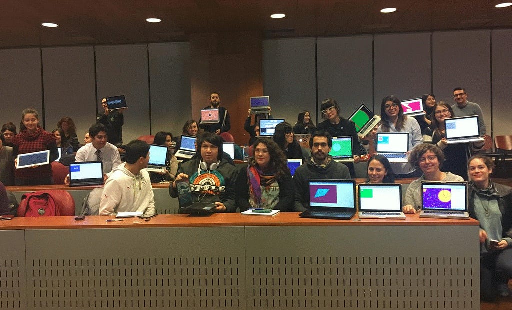 Large group of smiling artists display their laptops with first colorful sketches made with p5.js