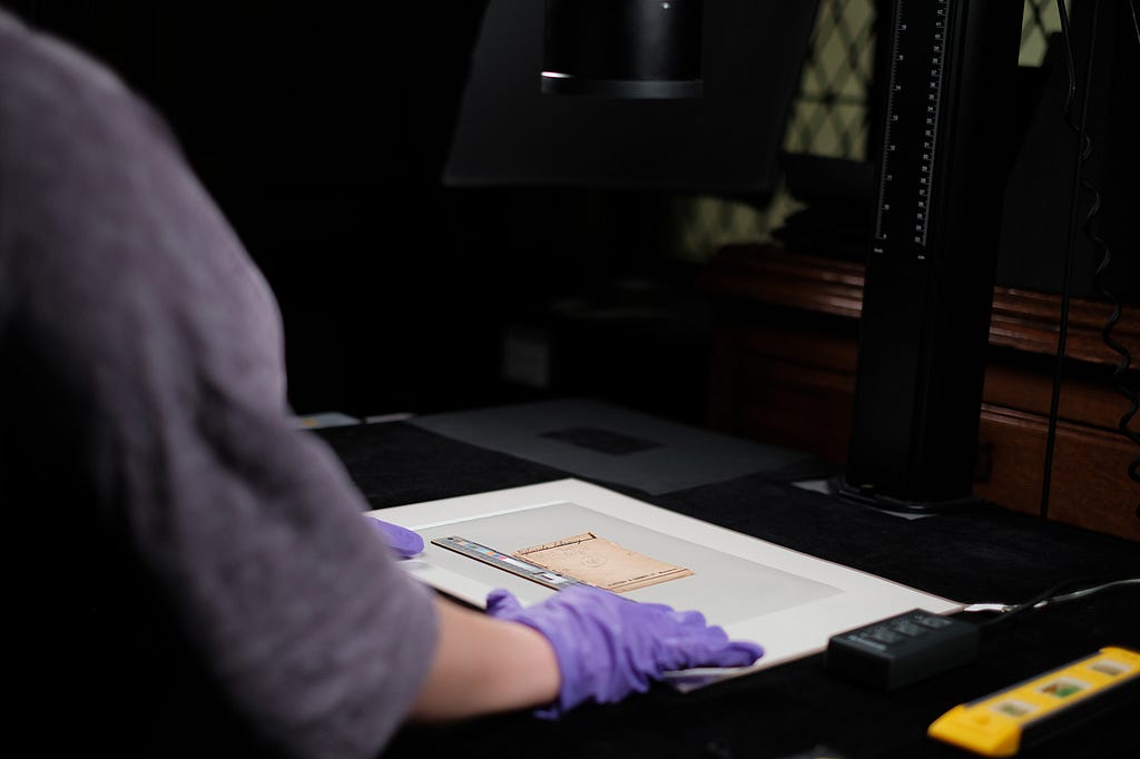 Millie wearing nitrile gloves preparing an envelope for digitisiation with reflected light