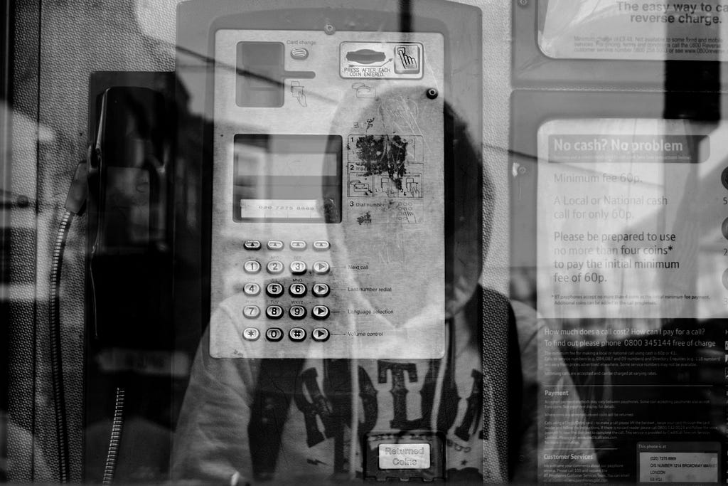 A man’s reflection looking at telephone