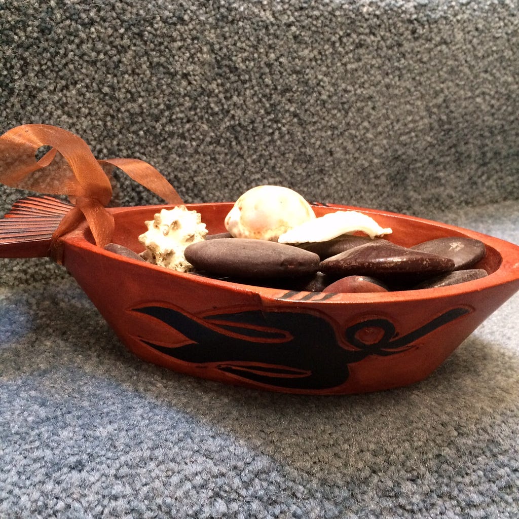 souvenir hand-carved wooden bowl, shaped like a fish and filled with shells