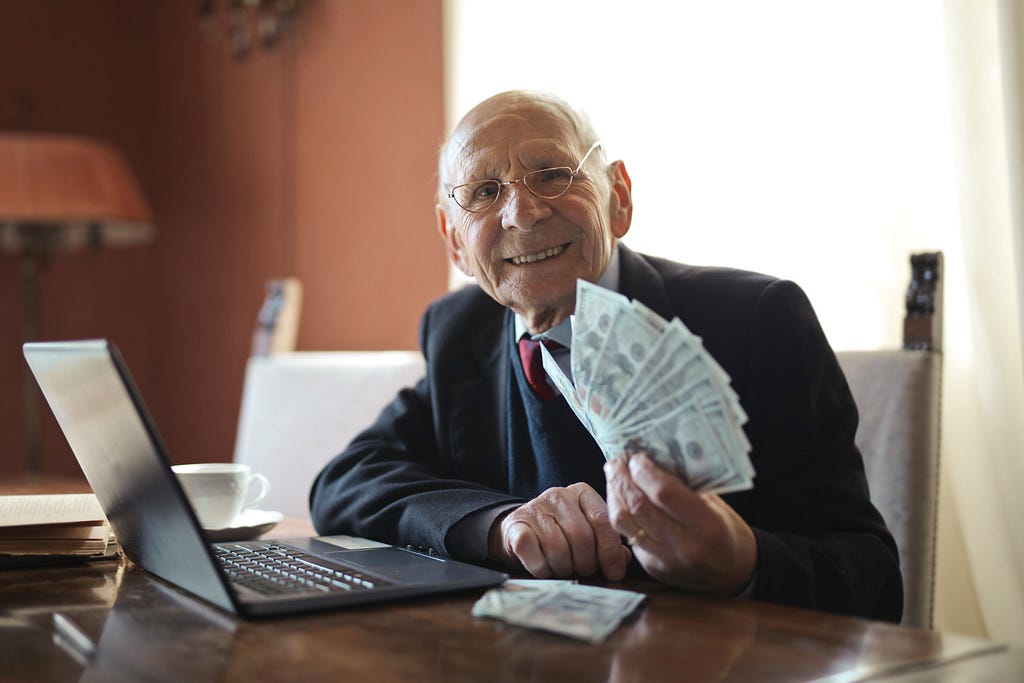 Elder business man, smiling, holding large amount of cash.
