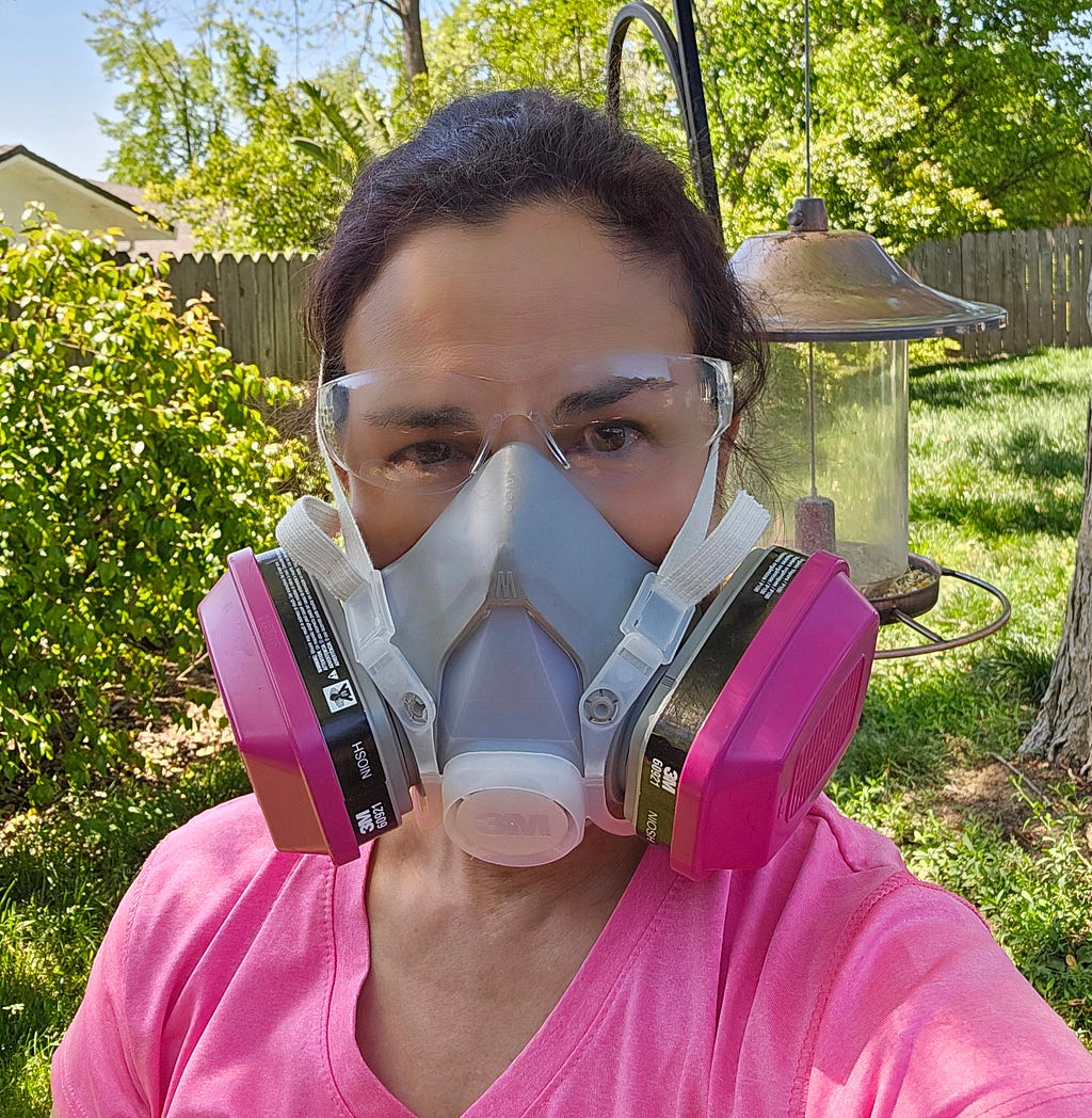 picture of author in a P-100 respirator and clear eye glasses in her yard