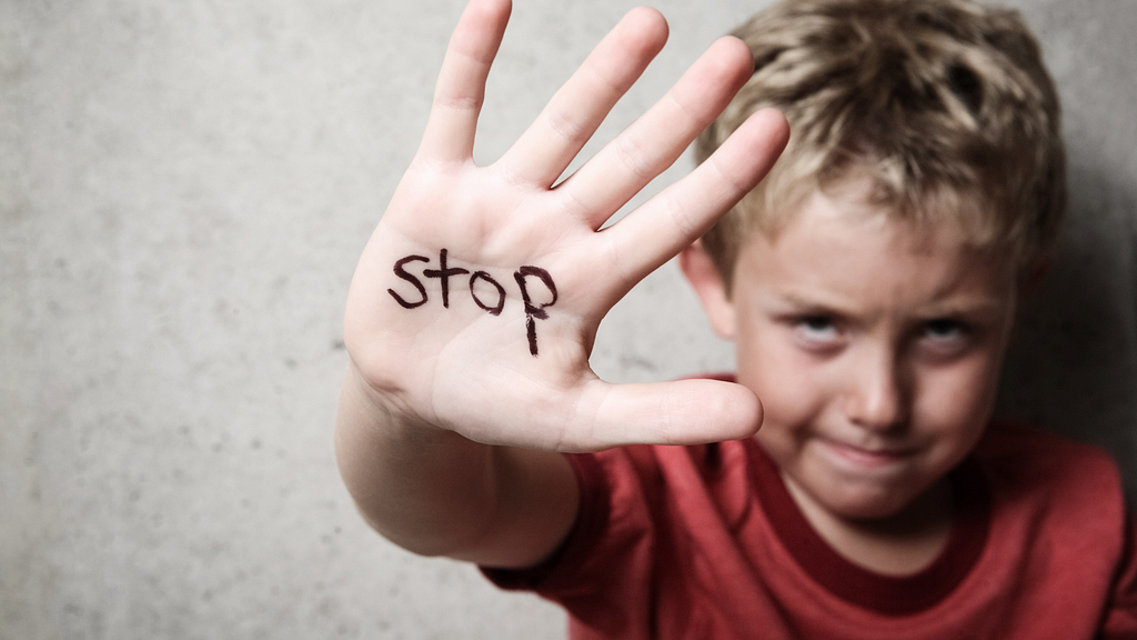 An abused child with the word “Stop” written on their hand.