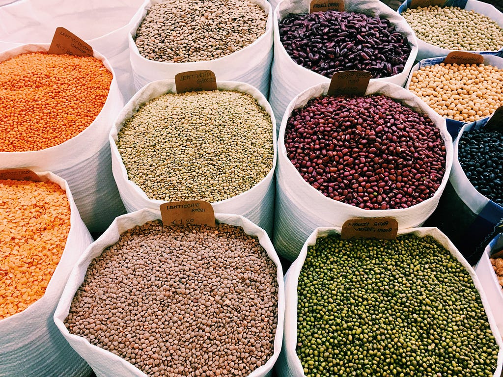An imagine showing variety of legumes, pulses and lentils stored in big containers in grocery store / pantry