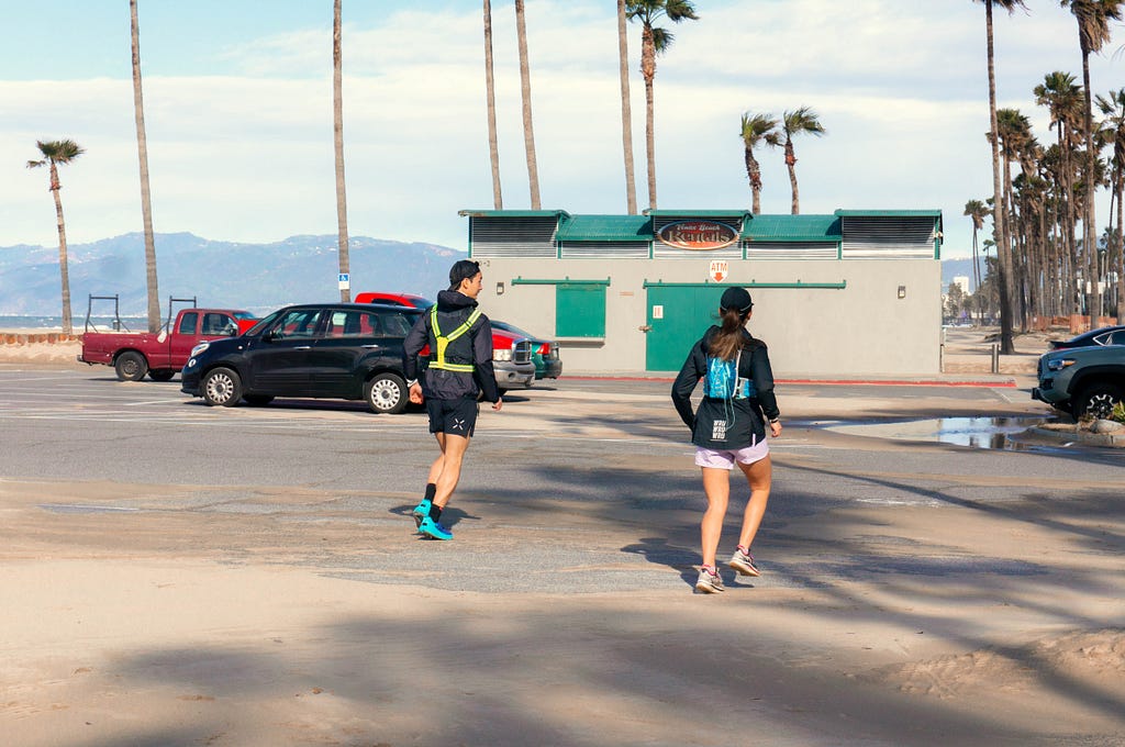 Two runners setting off in a parking lot next to the beach