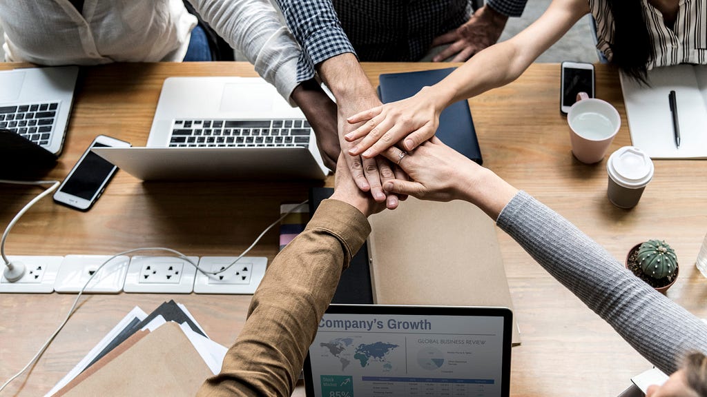 A picture of co-workers agreeing by placing their palms on each other.