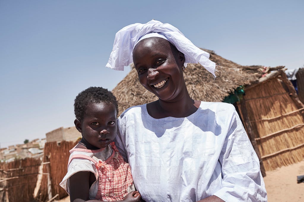 Ndéye Fall holds her youngest child outside of their home in Senegal.