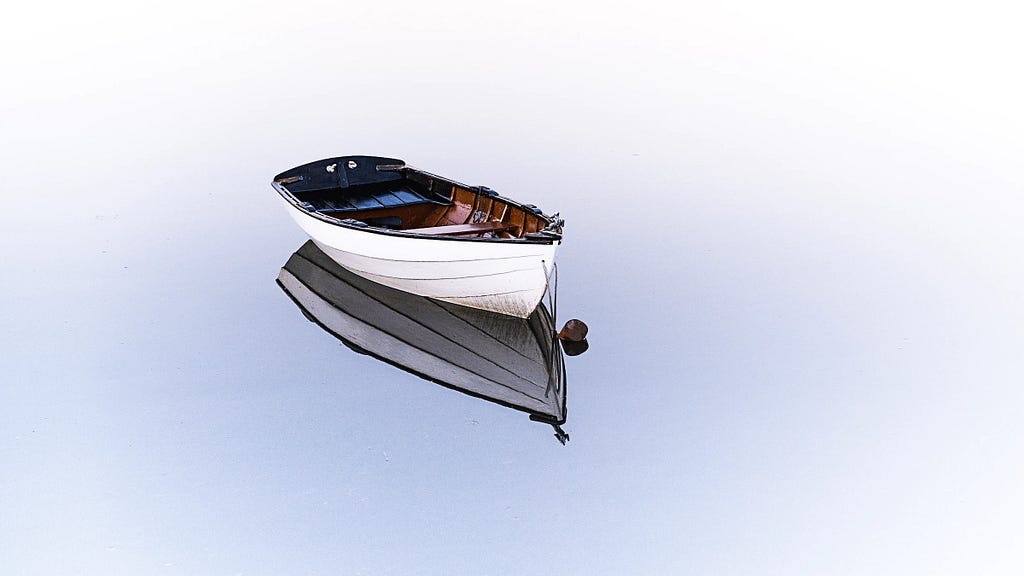 White wooden boat floating on light blue water.