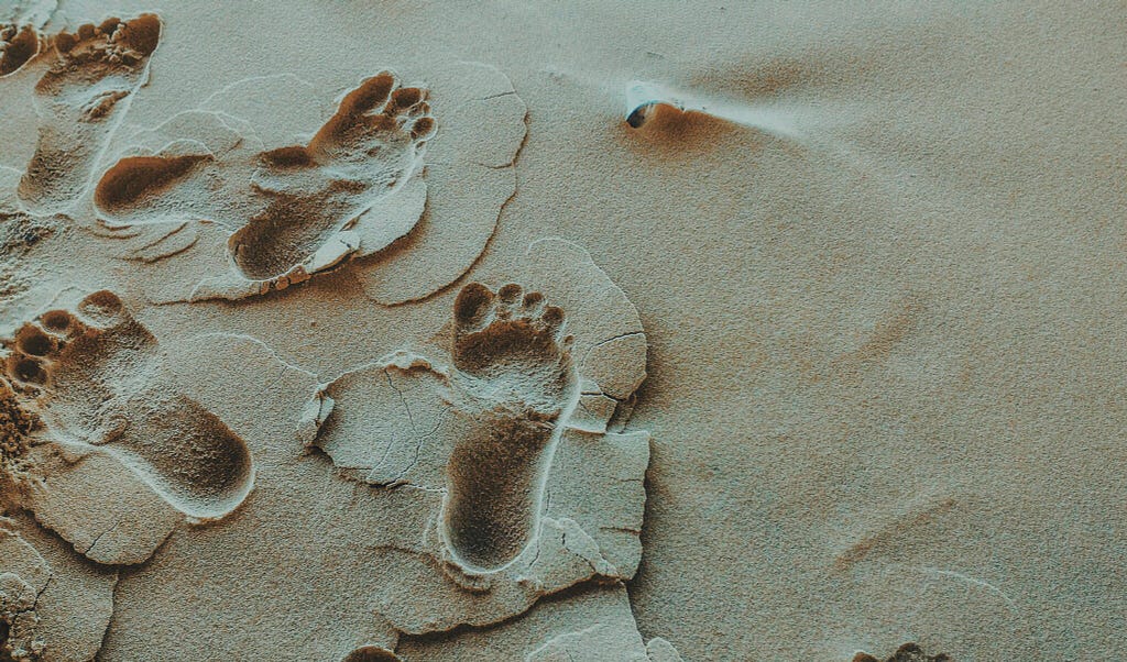 A few footprints in wet sand.