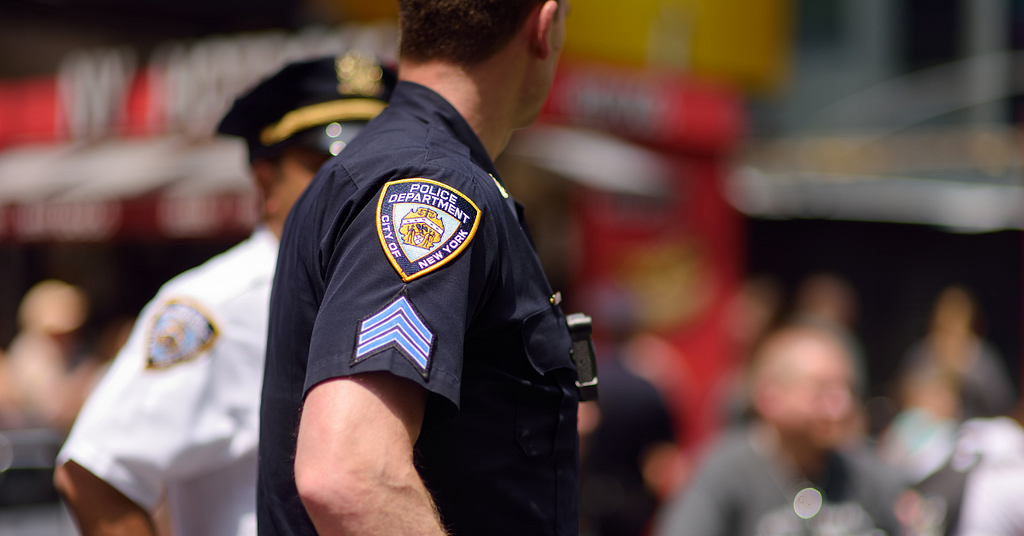 A police officer working for the police department of the city of New York is looking toward a group of people.