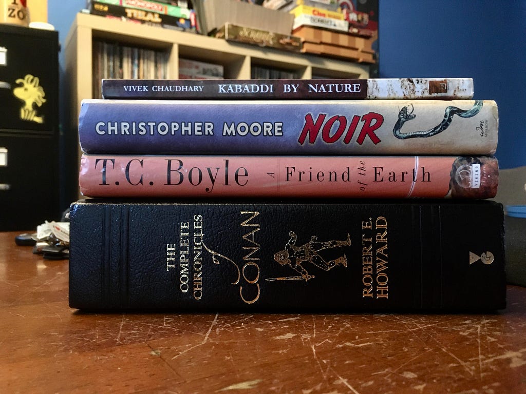 A stack of the four books referenced in the article on a dining room table.