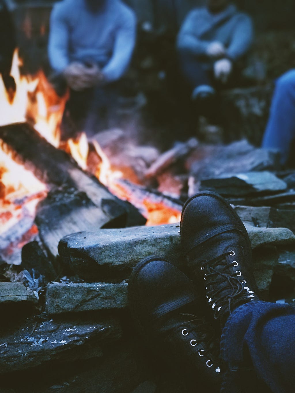Boots propped up on a rock while gathered around a campfire.