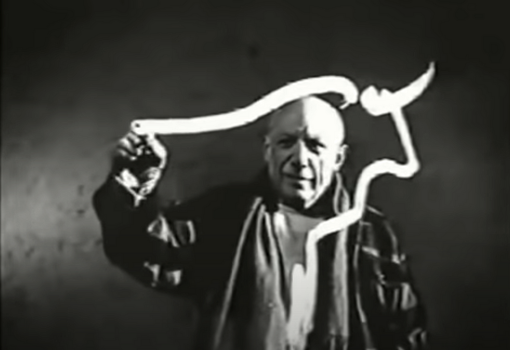 Pablo Picasso paints the outline of a bull on a glass panel.