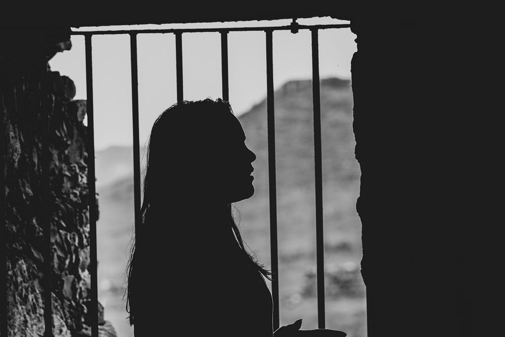 A sillouhette of a women framed by prison bars.