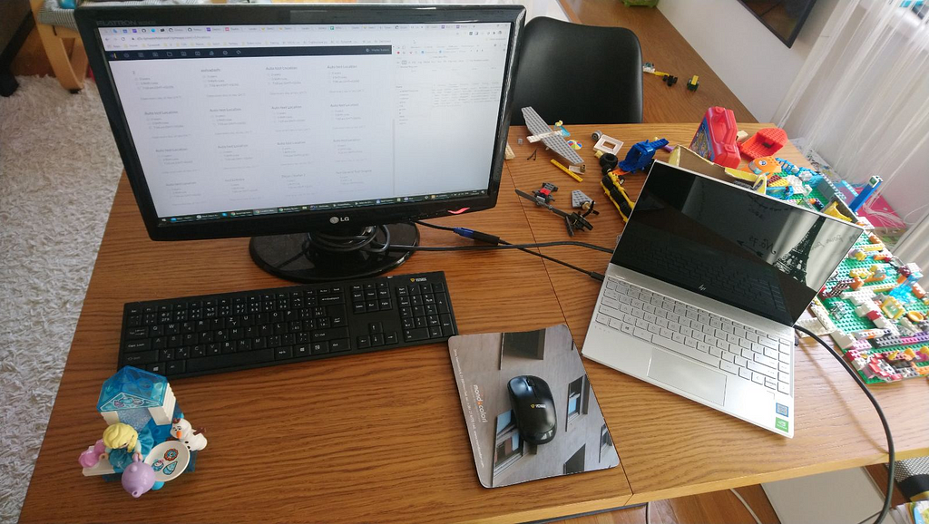 A desk with a computer, laptop, and Legos.