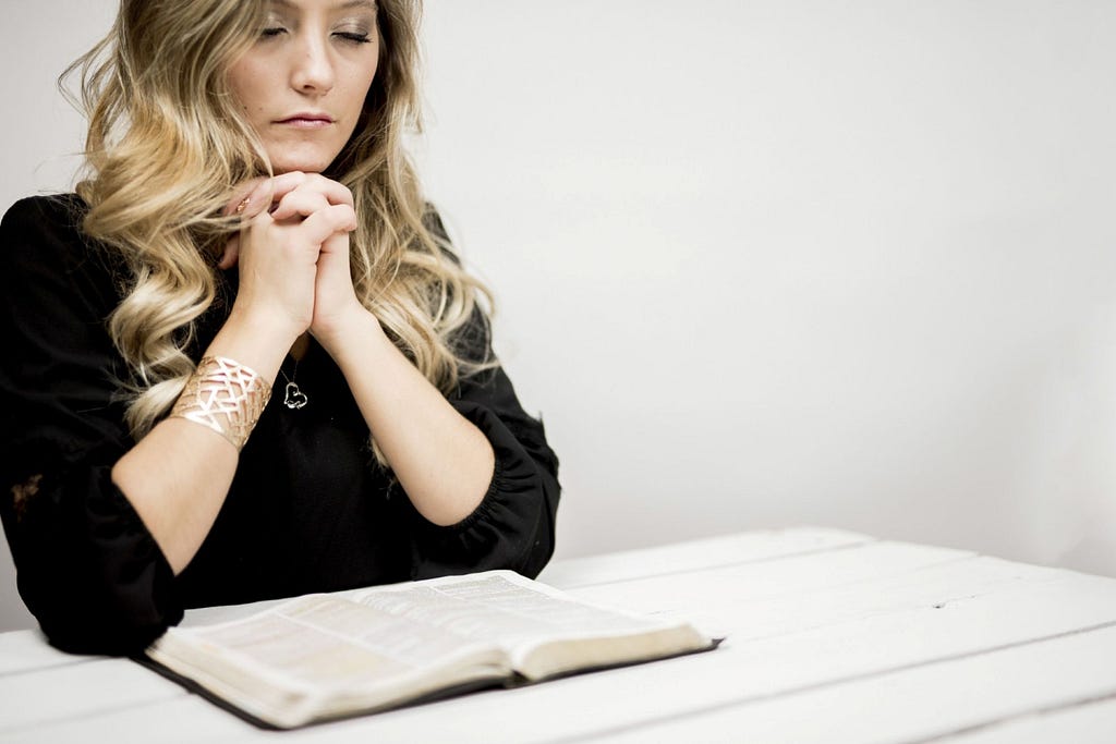 A woman praying over the Bible.