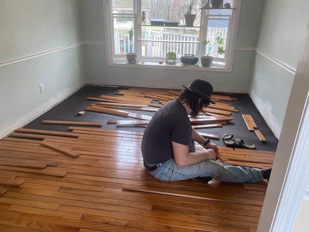 A photo of Mitch installing new hardwood floors in our living room.
