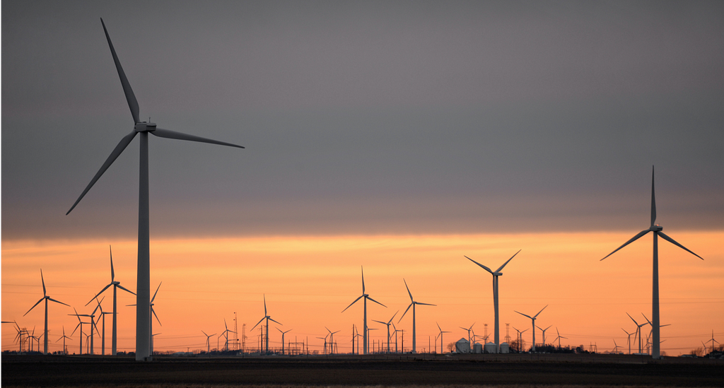 wind mills and a warm light of the sun that has just set in the background