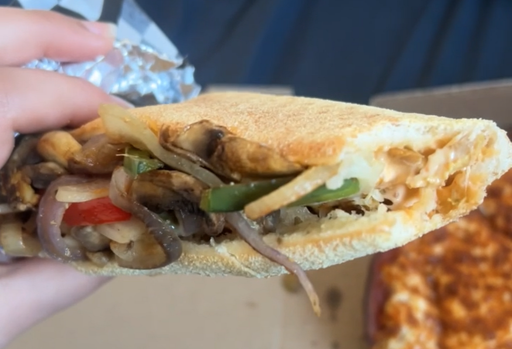 Close-up of the vegetables and chicken oozing out of the sandwich