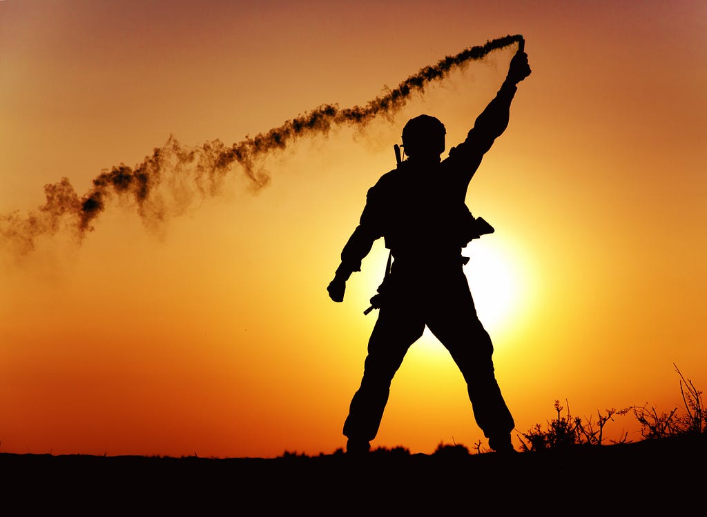 A soldier signaling with a flare in a sunset background