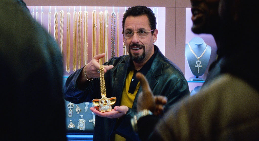 A scene from Uncut Gems: Howard shows off the diamond encrusted Furby chain.