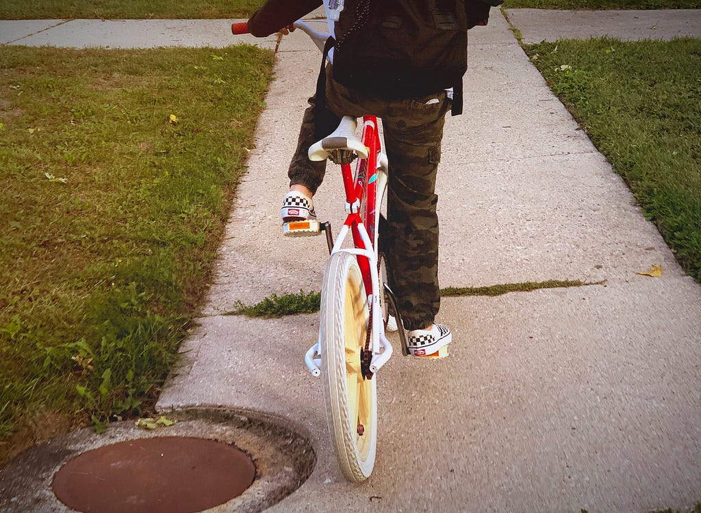 Rear view of a child with a backpack riding a BMX bike