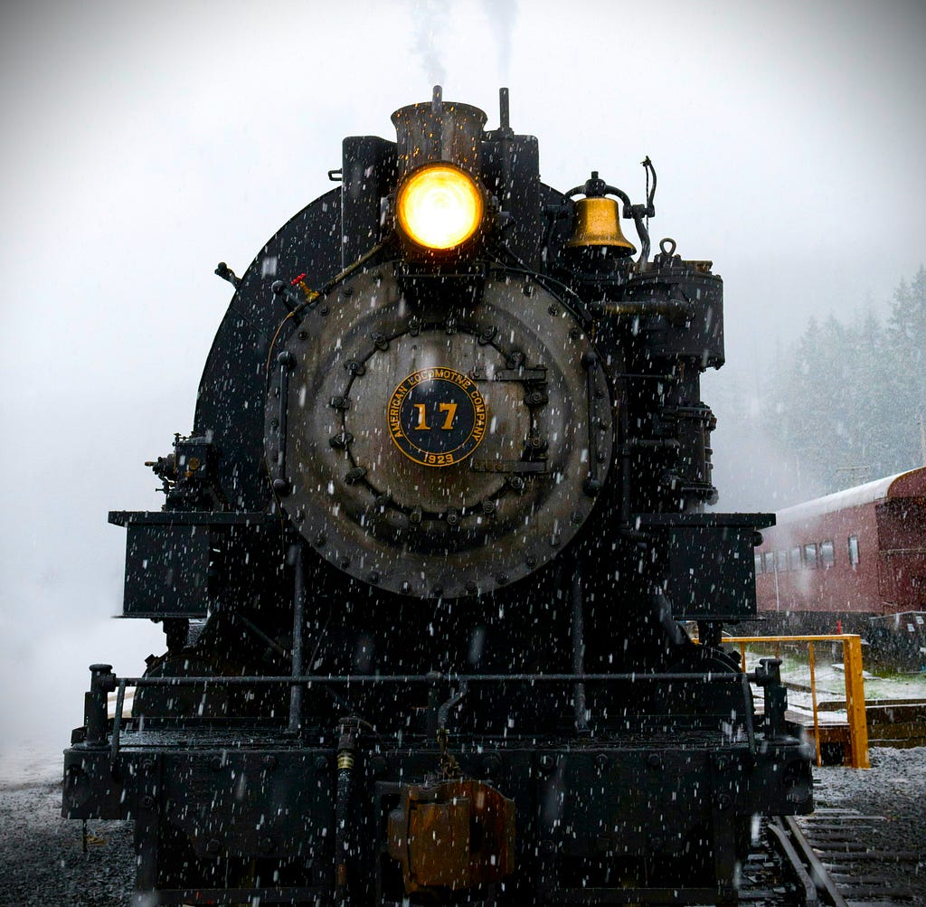 A steam locomotive with the light on.