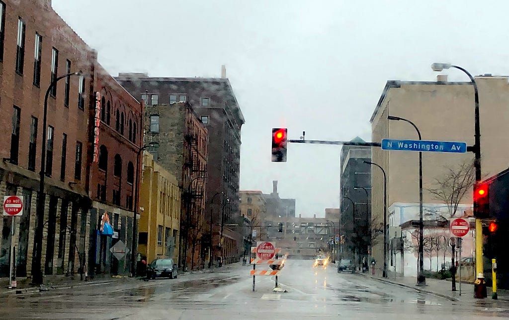 Desolate, rainy, empty city street, with red light and Do Not Enter signs.