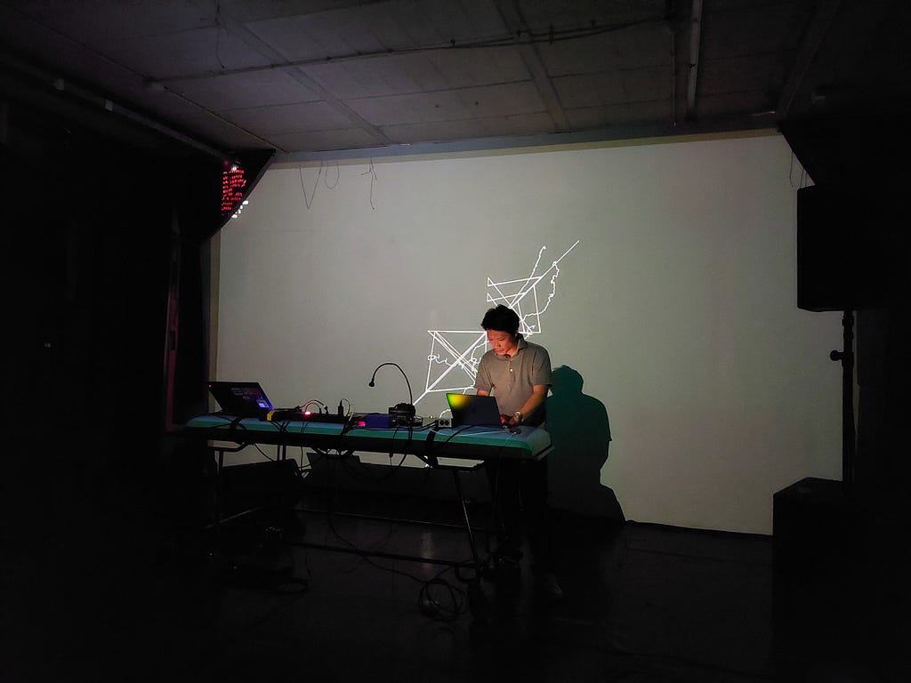 Yota Morimoto live coding with his visual work projected in the background