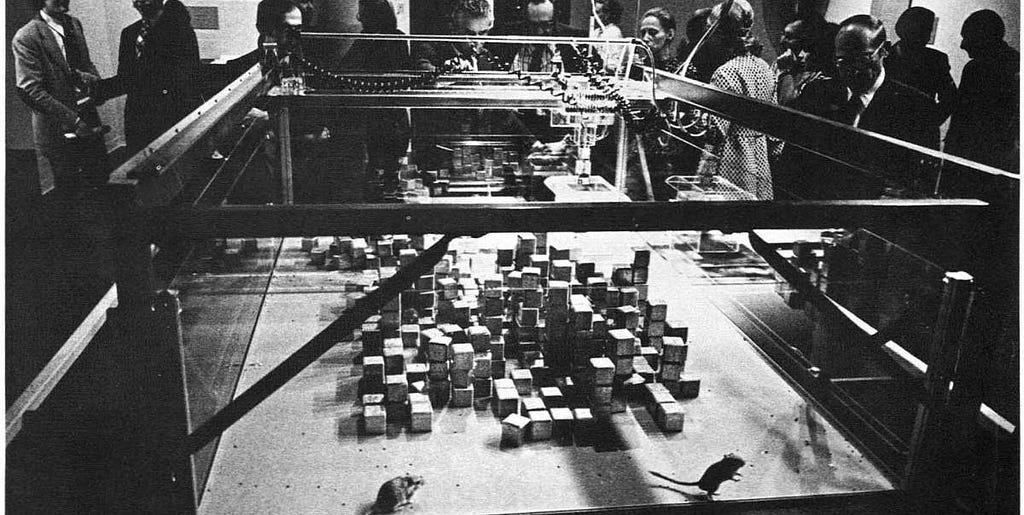 Photo of SEEK installation held at MIT in 1969 showing number of fabricated cubes that constantly reassembles by robotic arms. They are also some mouses moving in between those cubes.