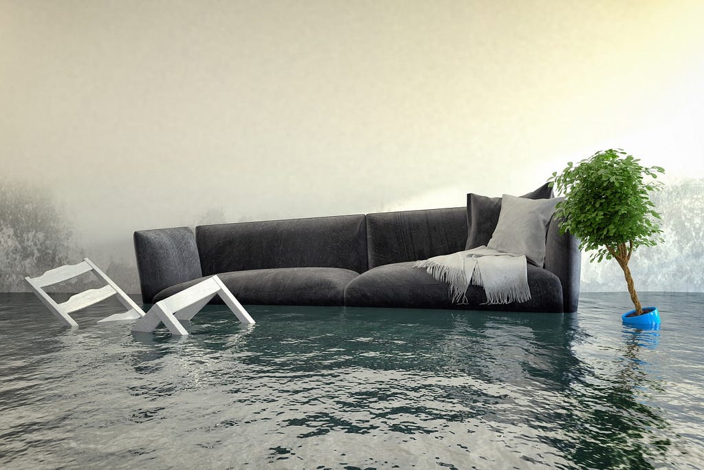 A sad scene of a grey couch floating in a flooded room