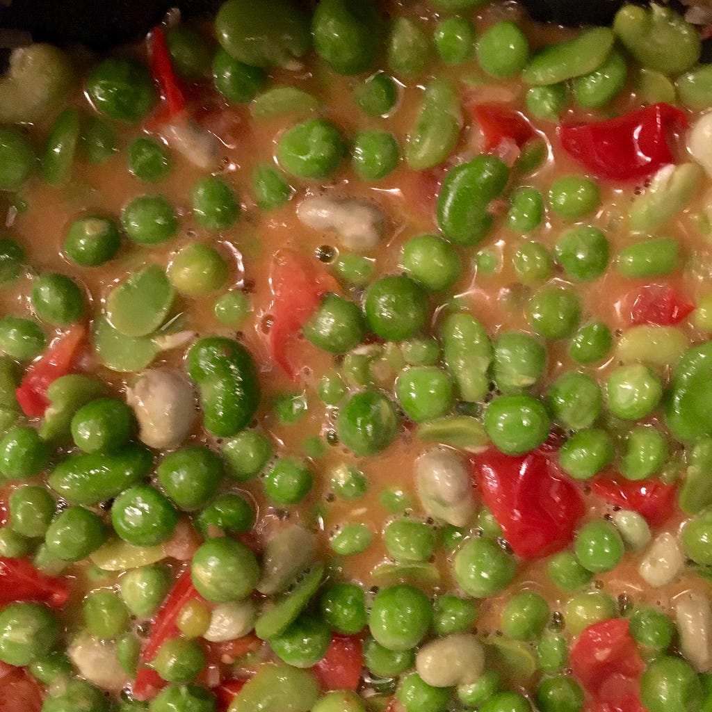 Closeup of the peas and dumplings, showing lots of sauce.