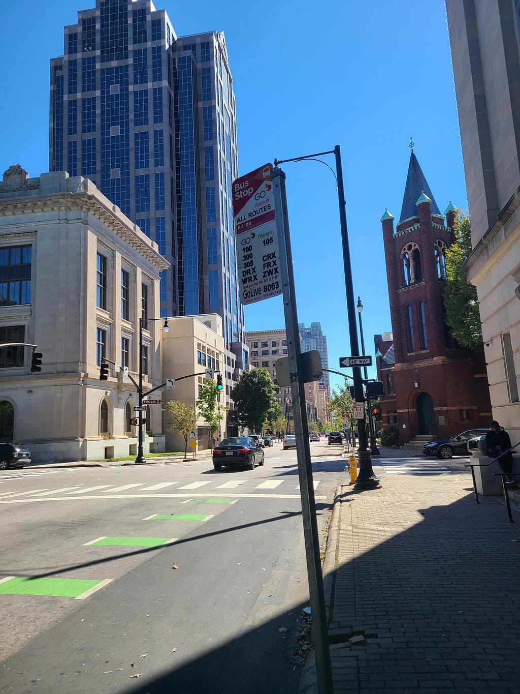 A bus stop sign with buildings in the background