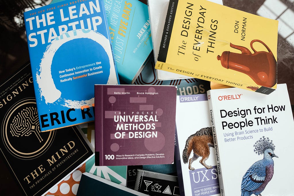 Livros em inglês dispostos de maneira aleatória. Alguns deles: The Design of everyday things, The lean startup, Design for How People Think e Universal methods of design.