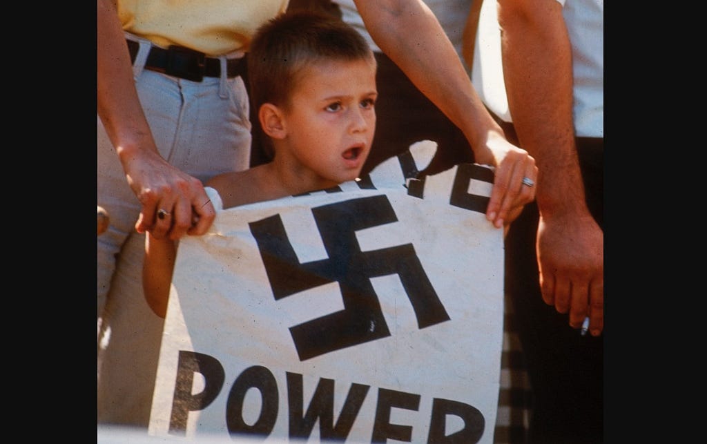 Picture of a boy holding a “White Power” sign with swastika