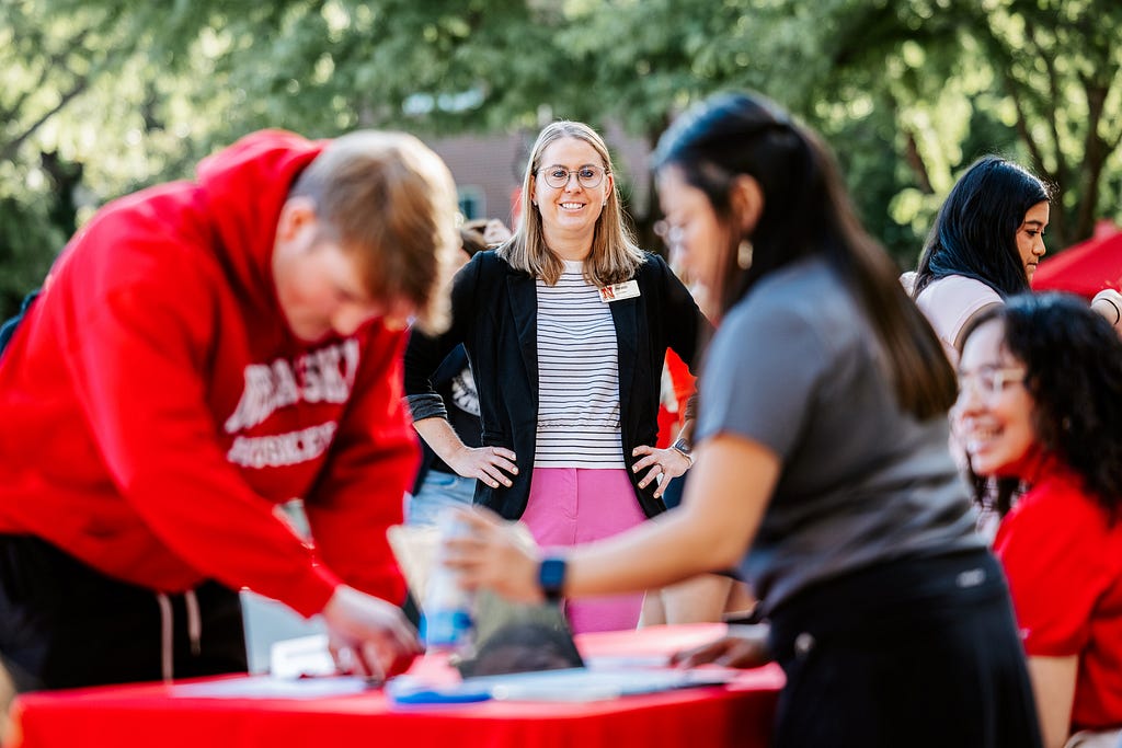 Jenni stands in the background as incoming students check in at welcome desks outside the union