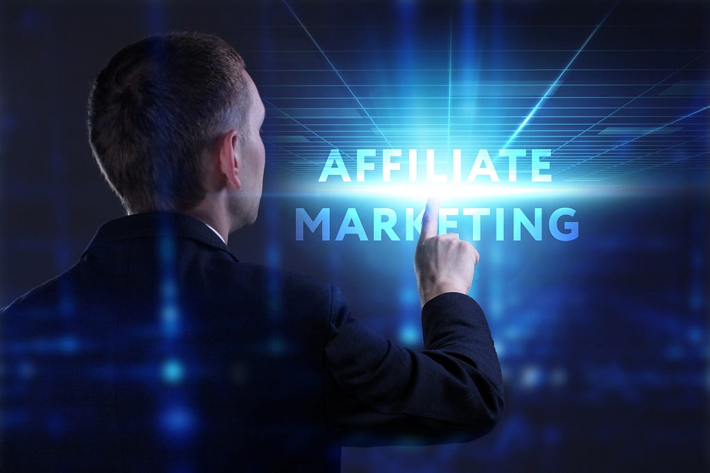 A businessman in a dark suit seen from behind, pointing at glowing blue text that reads “AFFILIATE MARKETING” floating in a futuristic digital space with emanating light rays and grid patterns.