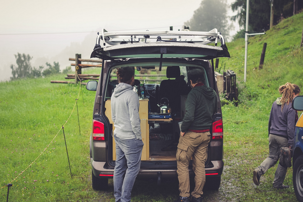 Converted car micro camper with kitchen and two men stood outside