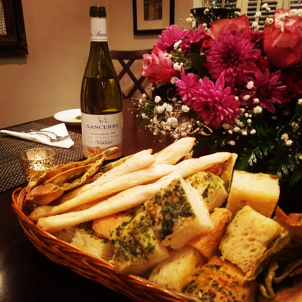 A bread basket of focaccia, grissini breadsticks, and a crisp grilled cracker