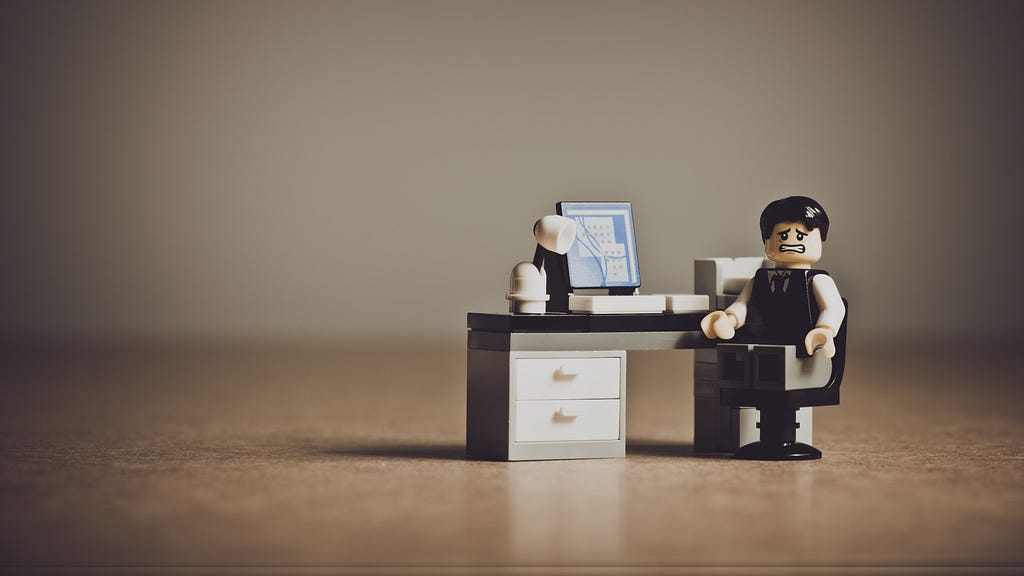 Image depicting a stressed out LEGO man sitting at his desk