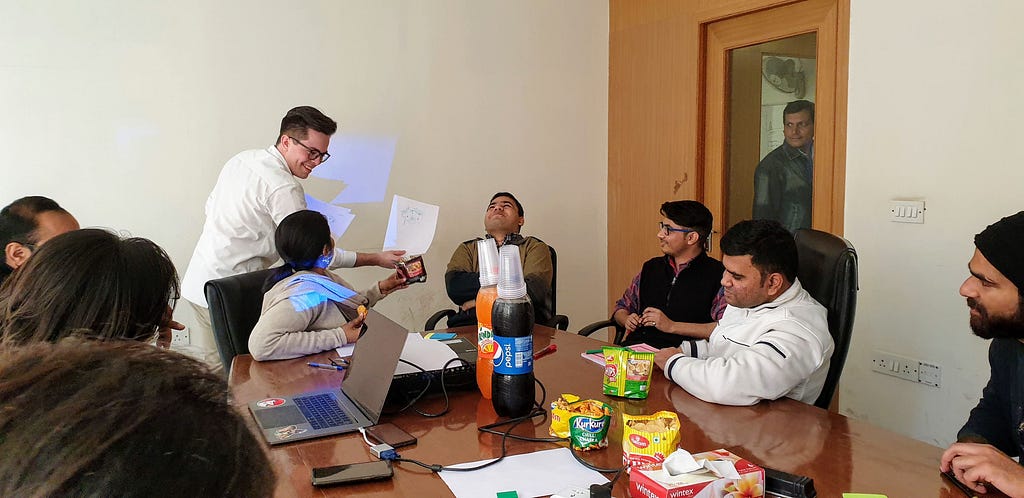 Workshop coordinator holding up an image, while the workshop participant are laughing